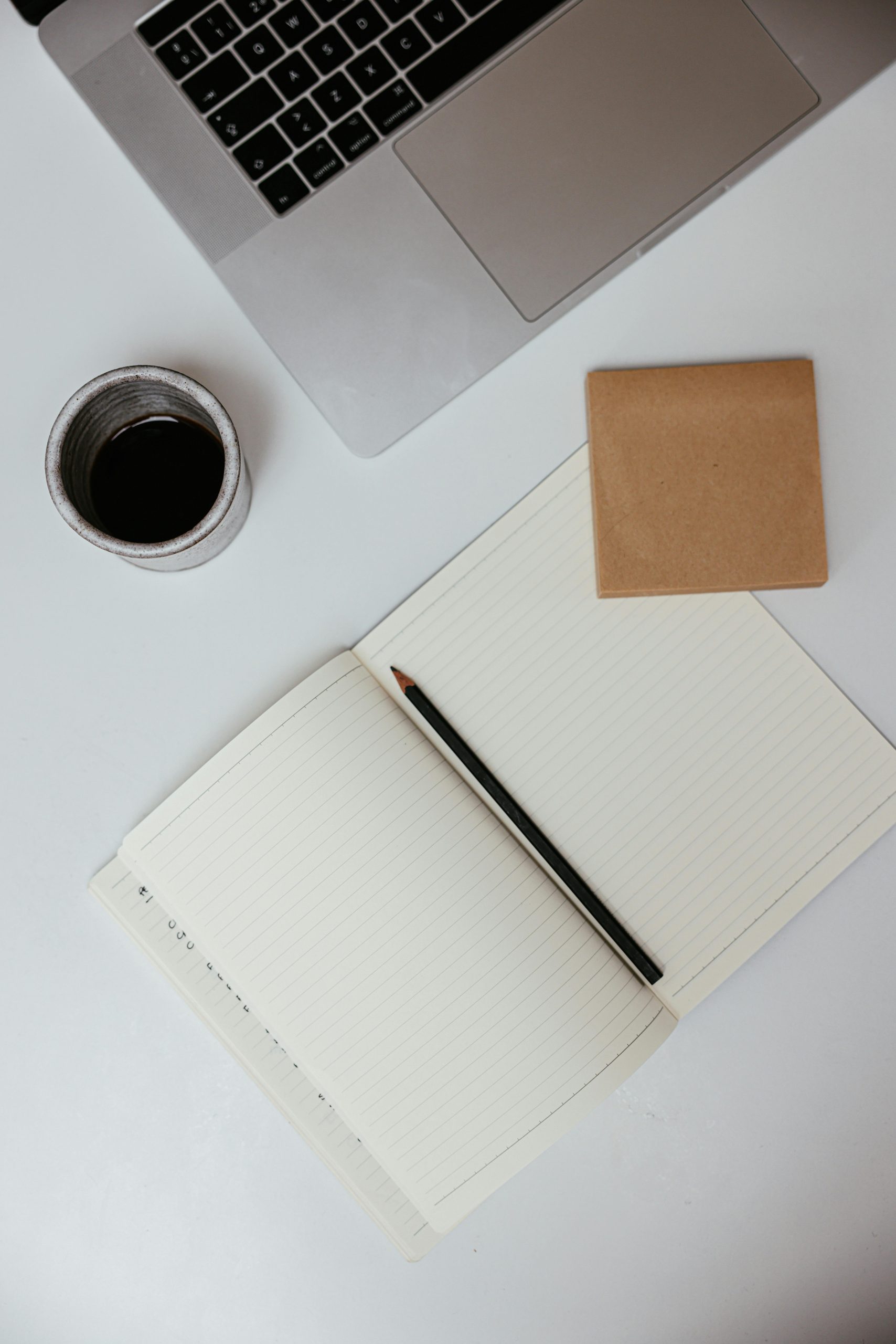 A flat lay of a workspace featuring a laptop, notebook, and coffee, ideal for productivity concepts.